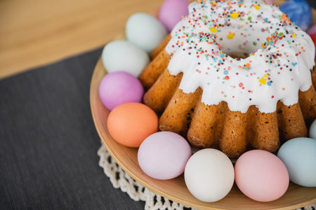 High angle view of sweet Easter cake and painted pastel colors eggs on table at home