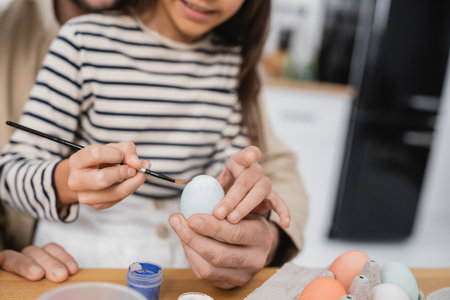 Cropped view of child coloring Easer egg near father at homeの写真素材