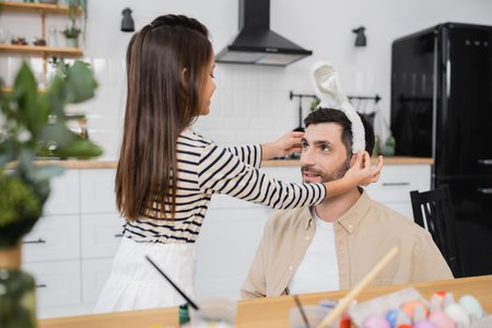 Girl wearing Easter headband on dad in kitchenの写真素材