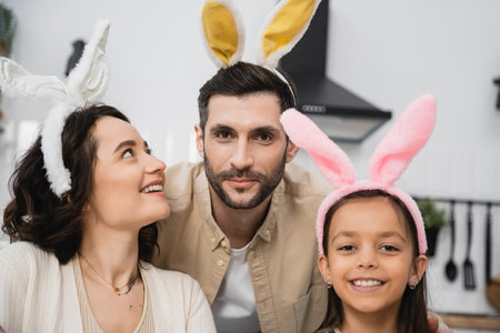 Cheerful family in Easter headbands looking at camera at homeの写真素材