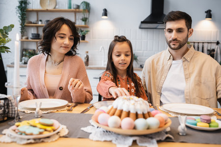 Family sitting near Easter dinner and candle on table at homeの写真素材