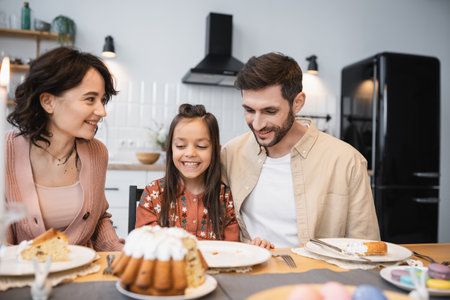 Smiling family with daughter having Easter dinner in kitchen