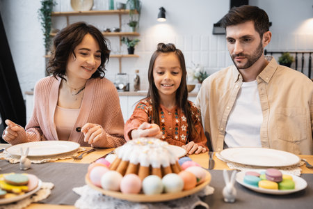 Smiling kid taking Easter egg during dinner with parents at homeの写真素材
