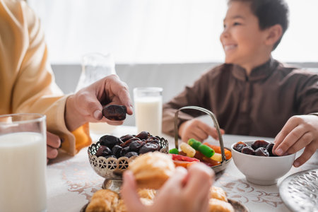 Muslim man taking date fruit near kids during suhur breakfast at homeの写真素材