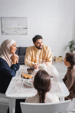 Smiling muslim family talking near food during ramadan at homeの写真素材