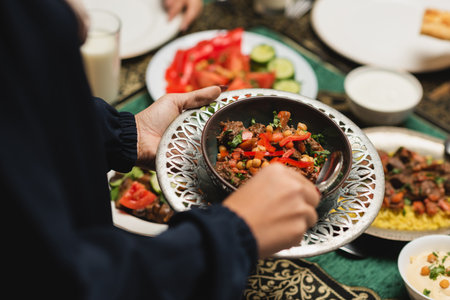 Cropped view of muslim woman holding delicious meal during ramadan at homeの写真素材