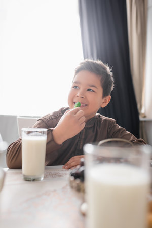Smiling muslim kid holding cevizli sucuk near ramadan breakfast at homeの写真素材