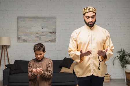 Middle eastern man and child praying during salah at homeの写真素材