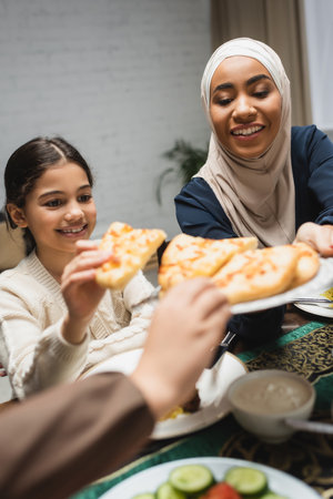 African american woman in hijab holding pita bread near kids during ramadan