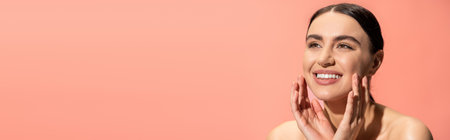 happy young woman with bare shoulders touching soft cheeks isolated on pink, banner