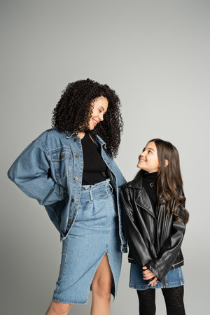 Smiling mother and daughter looking at each other isolated on greyの写真素材