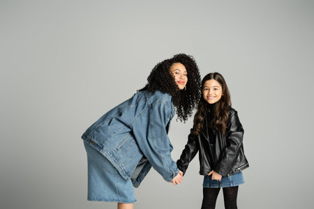 Trendy mother and daughter holding hands isolated on greyの写真素材