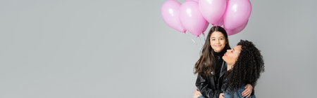 Smiling preteen girl hugging mother near balloons isolated on grey, bannerの写真素材