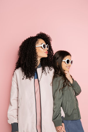 Trendy woman and girl in sunglasses and bomber jackets on pink backgroundの写真素材