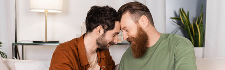 Side view of bearded gay couple sitting on couch at home, bannerの写真素材
