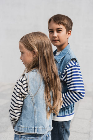 well dressed children in denim outfits looking at camera while standing outdoorsの写真素材
