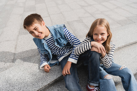 high angle view of happy and well dressed children sitting on stairs in urban streetの写真素材