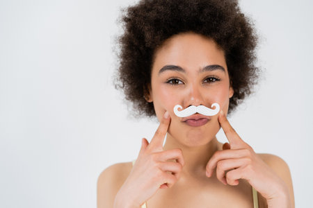 African american woman with paper moustache looking at camera isolated on greyの写真素材