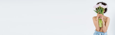 Shirtless african american woman holding tulips near face isolated on grey, bannerの写真素材