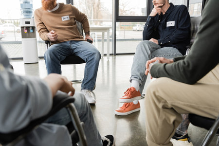 Cropped view of people sitting in circle during alcoholics meeting in rehab centerの写真素材