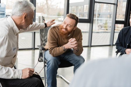 Mature man comforting smiling person with alcohol addiction in rehab centerの写真素材