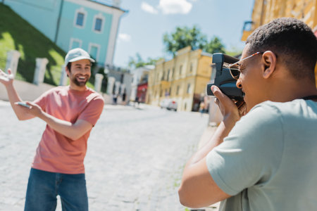 african american man with vintage camera taking photo of happy tourist pointing with hands on Andrews descent in Kyivの写真素材
