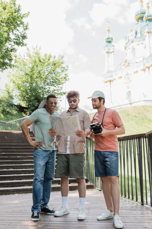 interracial travelers with city map standing on stairs near St Andrews church on blurred background in Kyivの写真素材
