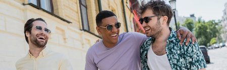 Positive interracial men in sunglasses walking on Andrews descent in Kyiv, banner
