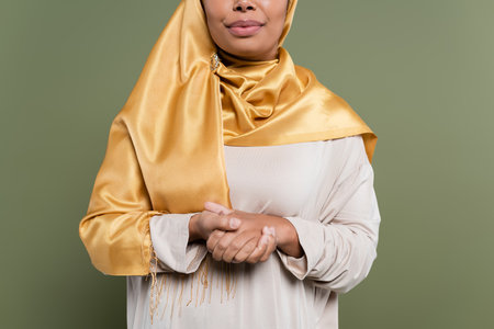 Cropped view of multiracial woman in hijab standing isolated on greenの写真素材