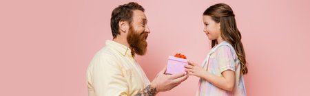 Side view of tattooed father giving present to daughter isolated on pink, bannerの写真素材