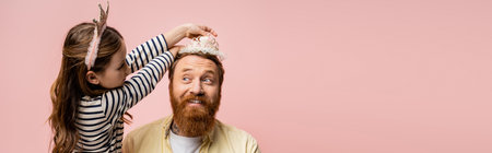 Child wearing crown headband on smiling bearded dad isolated on pink, bannerの写真素材
