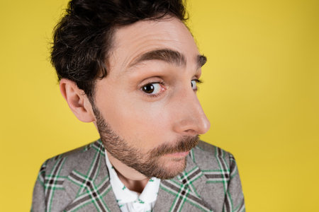 Wide angle view of bearded man in jacket looking at camera isolated on yellowの写真素材