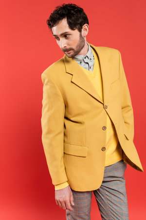 Charming guy posing in yellow jacket and looking away isolated on coralの写真素材