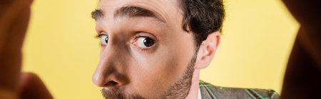 Cropped view of brunette man looking at camera isolated on yellow, bannerの写真素材