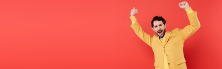 excited man with opened mouth gesturing while looking at camera on coral background, bannerの写真素材