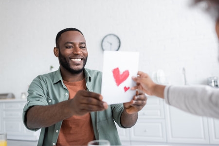 african american girl giving greeting card with drawn hearts to happy dad on fathers dayの写真素材