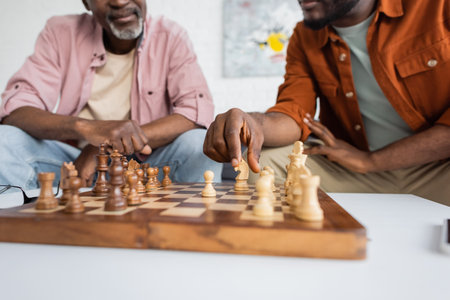 Cropped view of african american man playing chess with middle aged dad at homeの写真素材