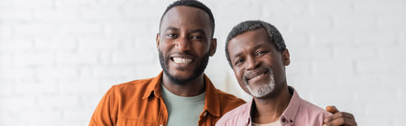 Happy african american man hugging middle aged dad at home, bannerの写真素材