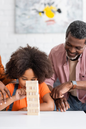 African american child playing wood blocks game with dad and grandfather at homeの写真素材