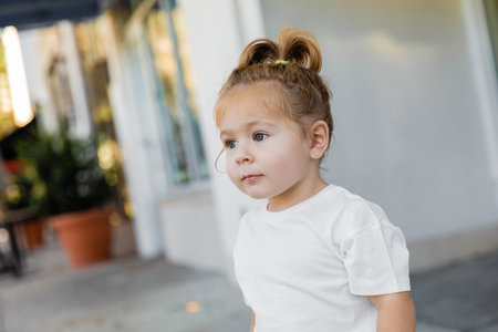 portrait of toddler girl with grey eyes looking away on street in Miamiの写真素材
