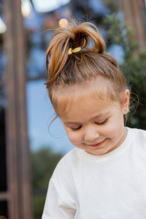 portrait of smiling toddler girl in white t-shirt smiling and looking downの写真素材