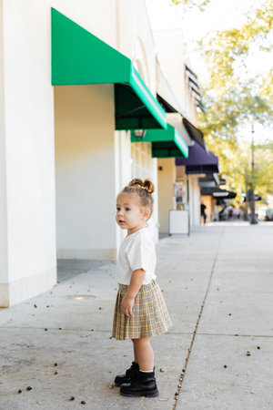 full length of toddler child in skirt and white t-shirt standing near acorns on ground in Miamiの写真素材