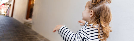 toddler baby girl in striped long sleeve shirt looking away while walking outside, bannerの写真素材