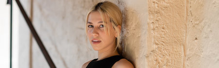 blonde woman in stylish outfit standing near wall of modern house in Miami, bannerの写真素材