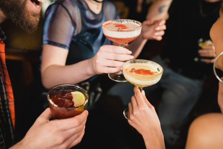 Cropped view of interracial friends holding different cocktails in barの写真素材