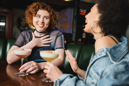 Multiethnic girlfriends having fun while talking cold foam cocktails in barの写真素材