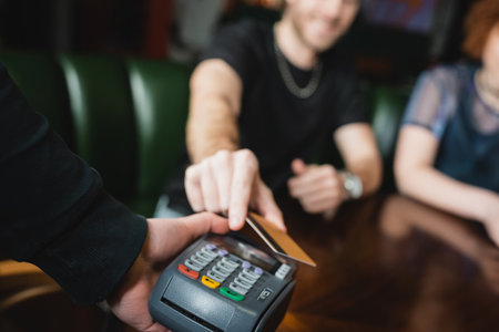 Cropped view of blurred man paying with credit card in barの写真素材