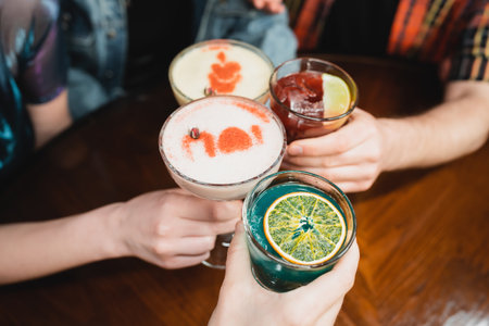 Cropped view of friends clinking with different cold cocktails in barの写真素材