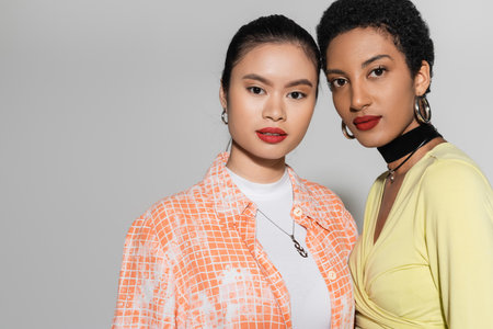 Portrait of young interracial models with red lips looking at camera on grey backgroundの写真素材