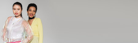 Positive interracial models with red lips looking at camera isolated on grey, bannerの写真素材